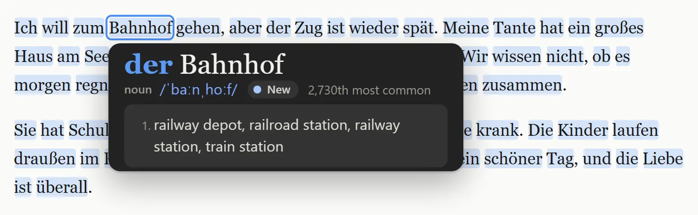 A German paragraph with the word Bahnhof hovered and its panel open, headed der Bahnhof with der in blue, followed by noun, the pronunciation and the meanings railway station and train station.