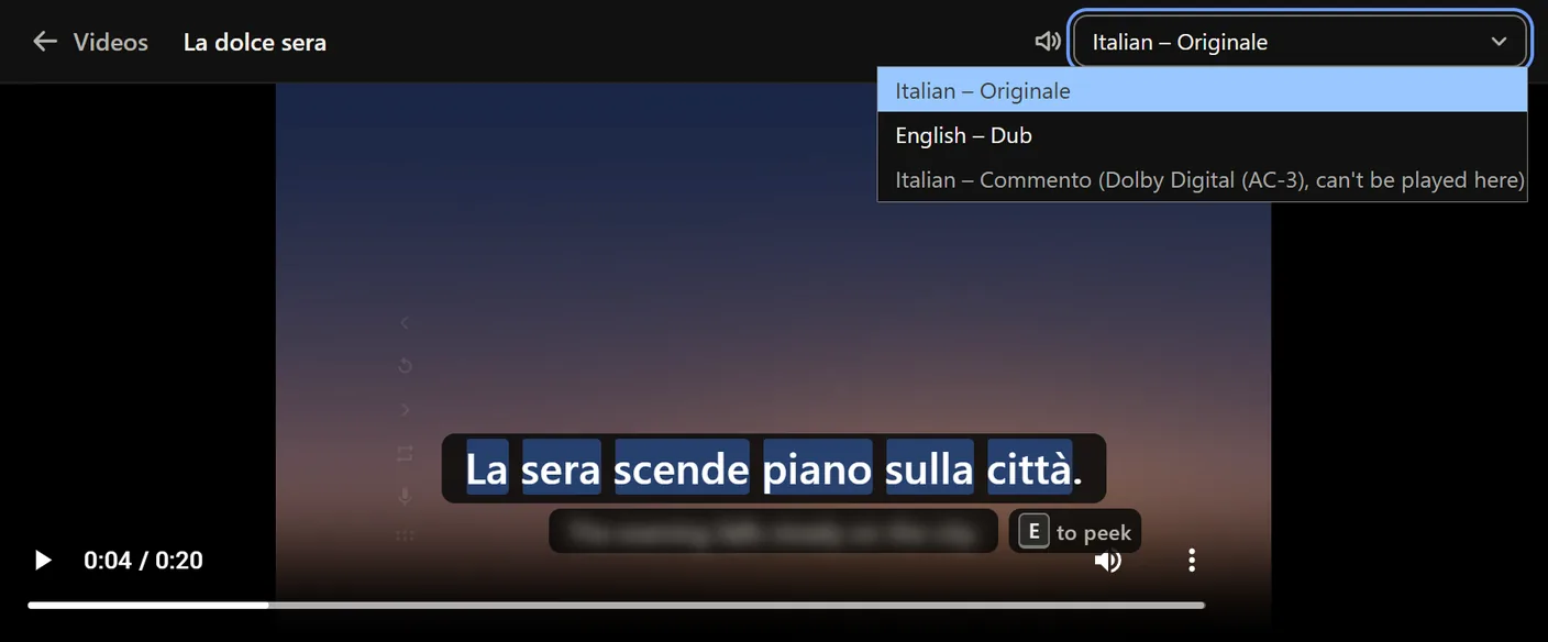 The Videos page player with its Sound track menu open over a dusk picture: Italian – Originale picked, English – Dub, and Italian – Commento greyed out as Dolby Digital that can't be played here; the subtitle La sera scende piano sulla città below.